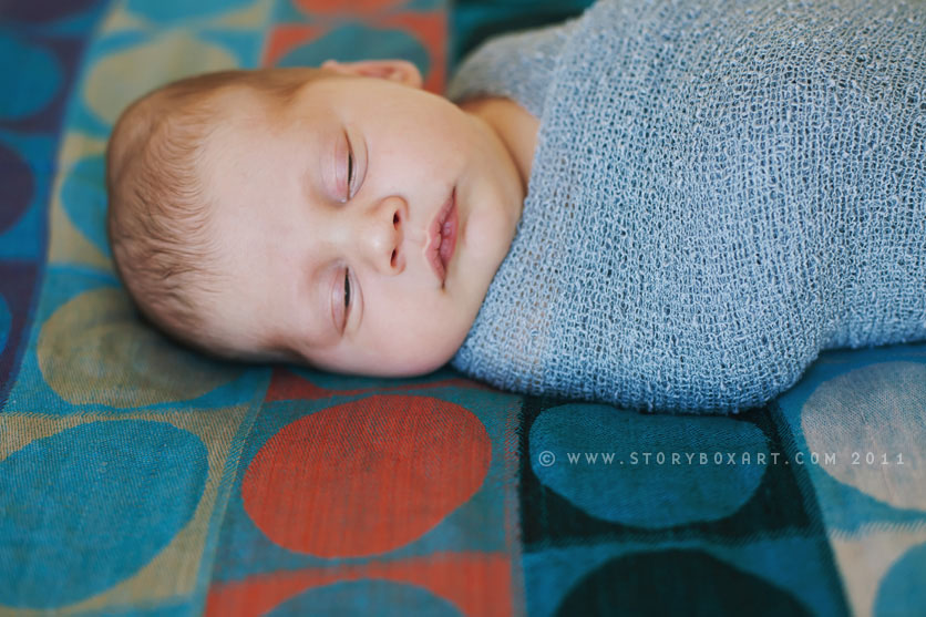 Newborn bundled up baby boy on bed